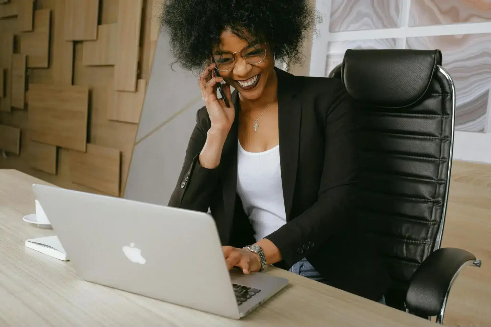 a smiling african-american woman scrolling through an apple laptop