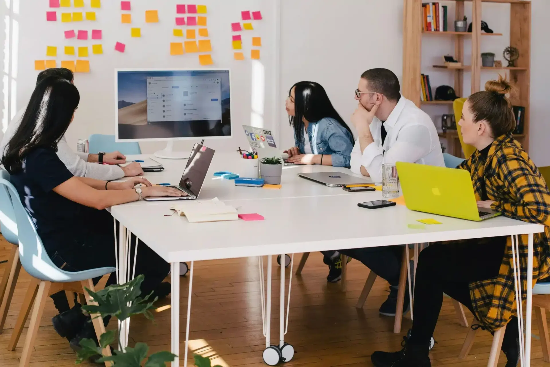 a group of people sitting around the table looking at the presentation on the screen